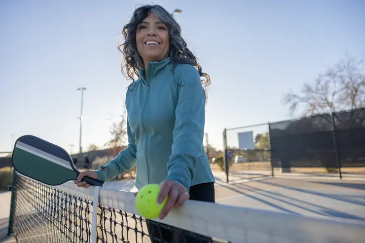 A woman smiling on a pickleball court